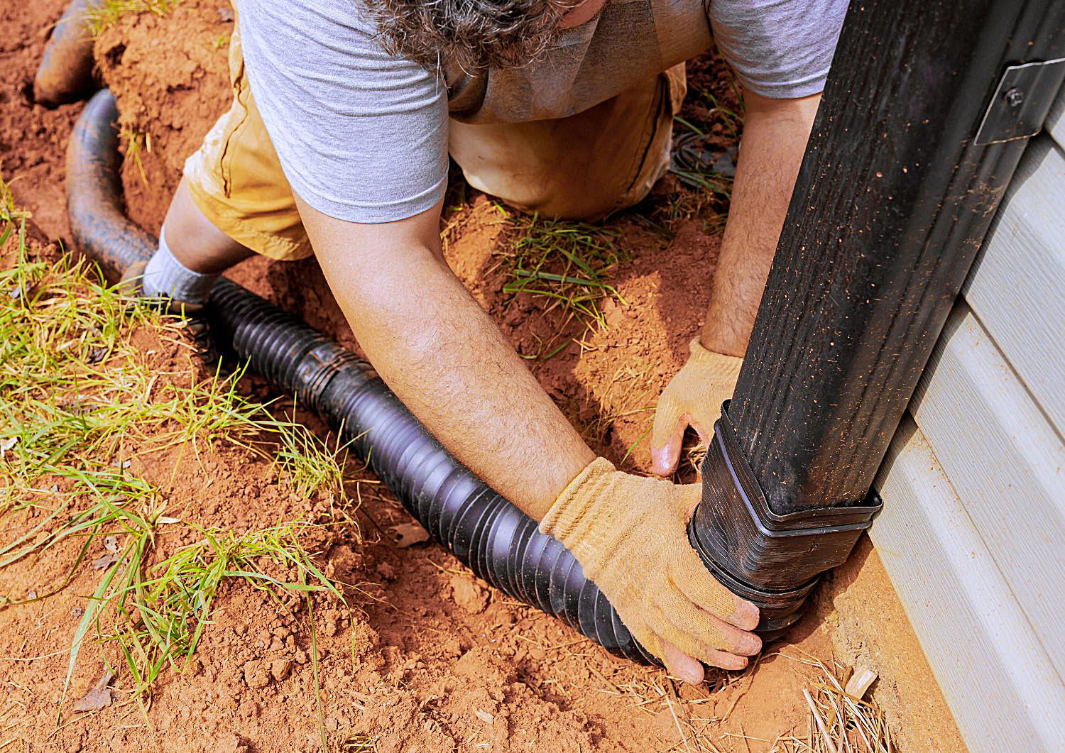 Crew installing a yard drainage system — catch basin and pipe — in a Mobile, AL yard.