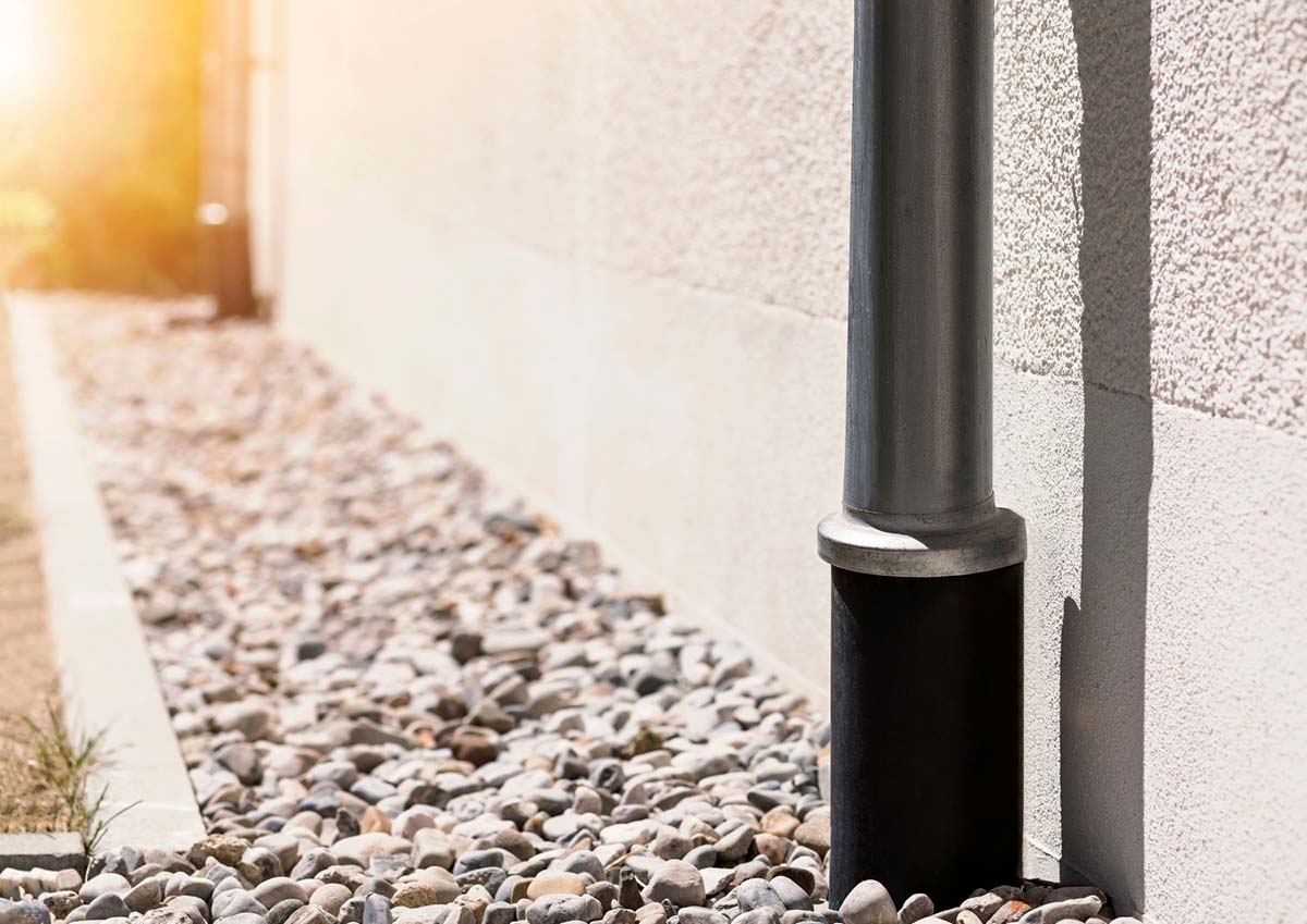 A gravel-and-pipe French drain channel carrying water away from a foundation in Mobile, AL.